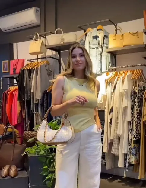 Look com regata amarela, calça branca e bolsa clara no interior da Majoy Solar