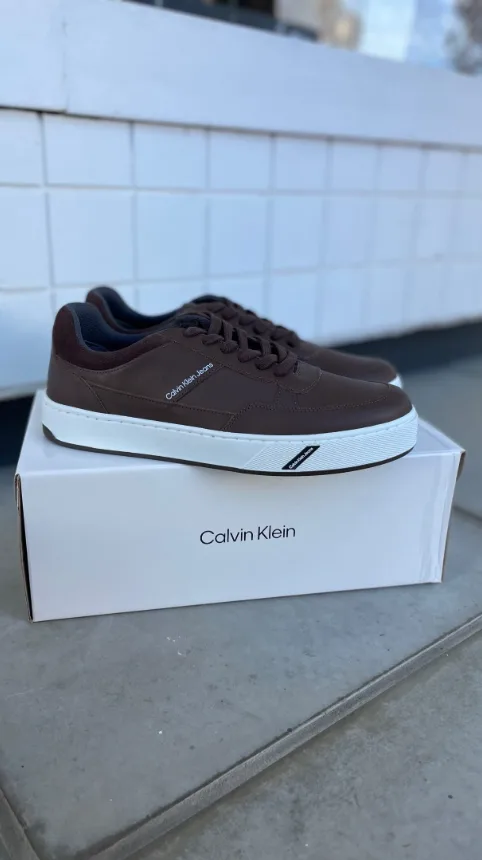 Tênis Calvin Klein marrom apoiado sobre a caixa
